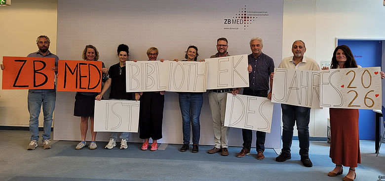 Neun Mitarbeitende von ZB&nbsp;MED halten auf mehreren Plakaten den Schriftzug "ZB&nbsp;MED ist Bibliothek des Jahres 2026" hoch